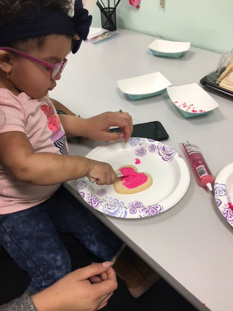 A child is decorating a heart shaped cookie
